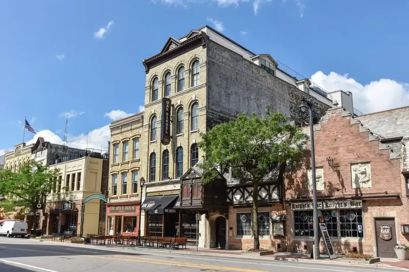A corner building on Old World Third Street with a half-timbered storefront and brick upper floors under a blue sky