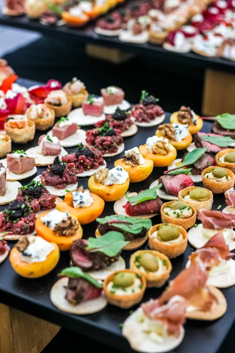 Hors d’oeuvres prepared for passed service, dozens of bites laid out on a black tray